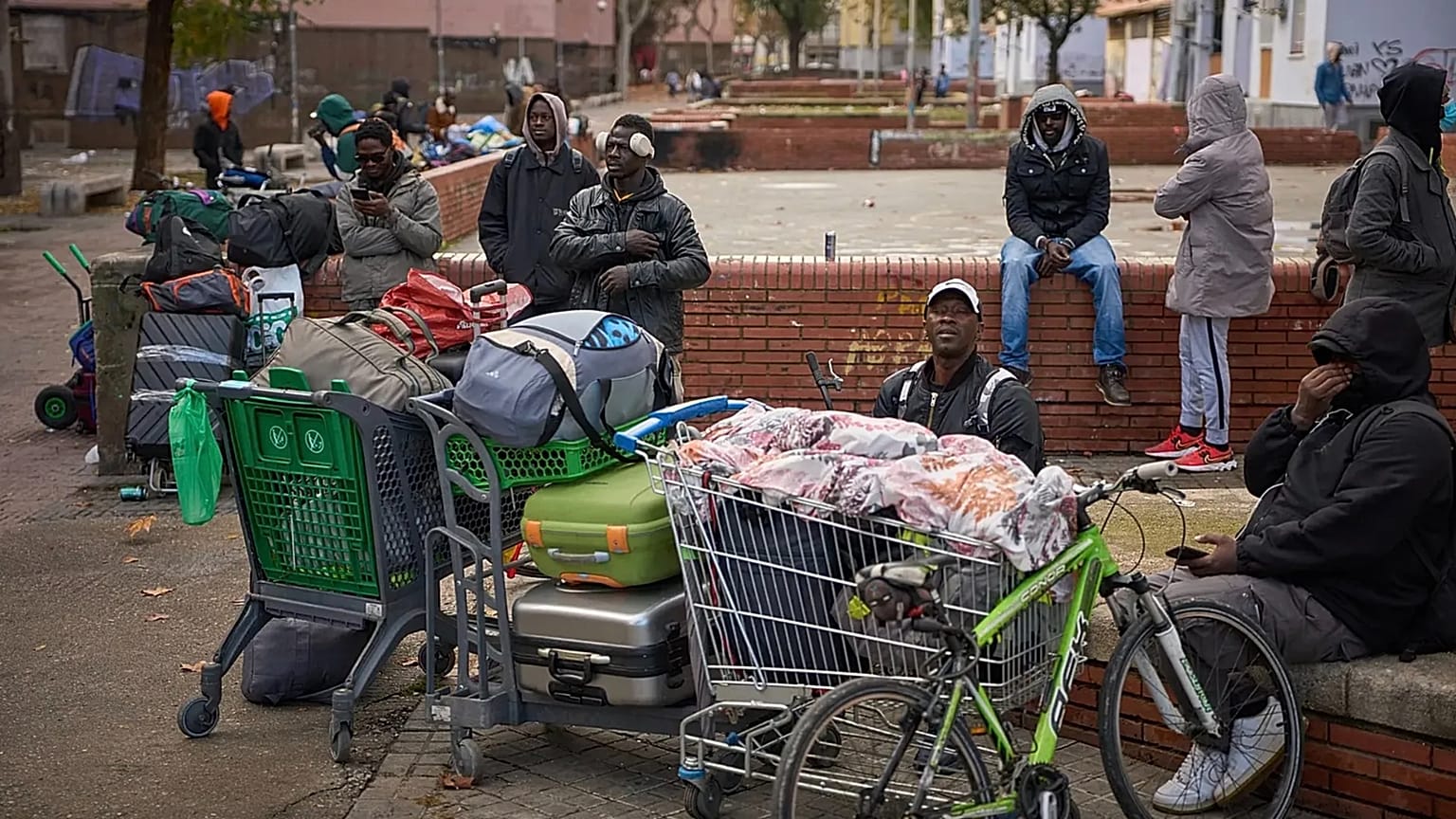 Göçmenler, Badalona'da yaşadıkları terk edilmiş bir okuldan polis tarafından tahliye edildikten sonra eşyalarıyla birlikte oturuyorlar, 17 Aralık 2025.