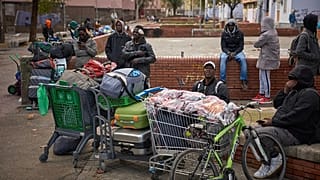 Göçmenler, Badalona'da yaşadıkları terk edilmiş bir okuldan polis tarafından tahliye edildikten sonra eşyalarıyla birlikte oturuyorlar, 17 Aralık 2025.