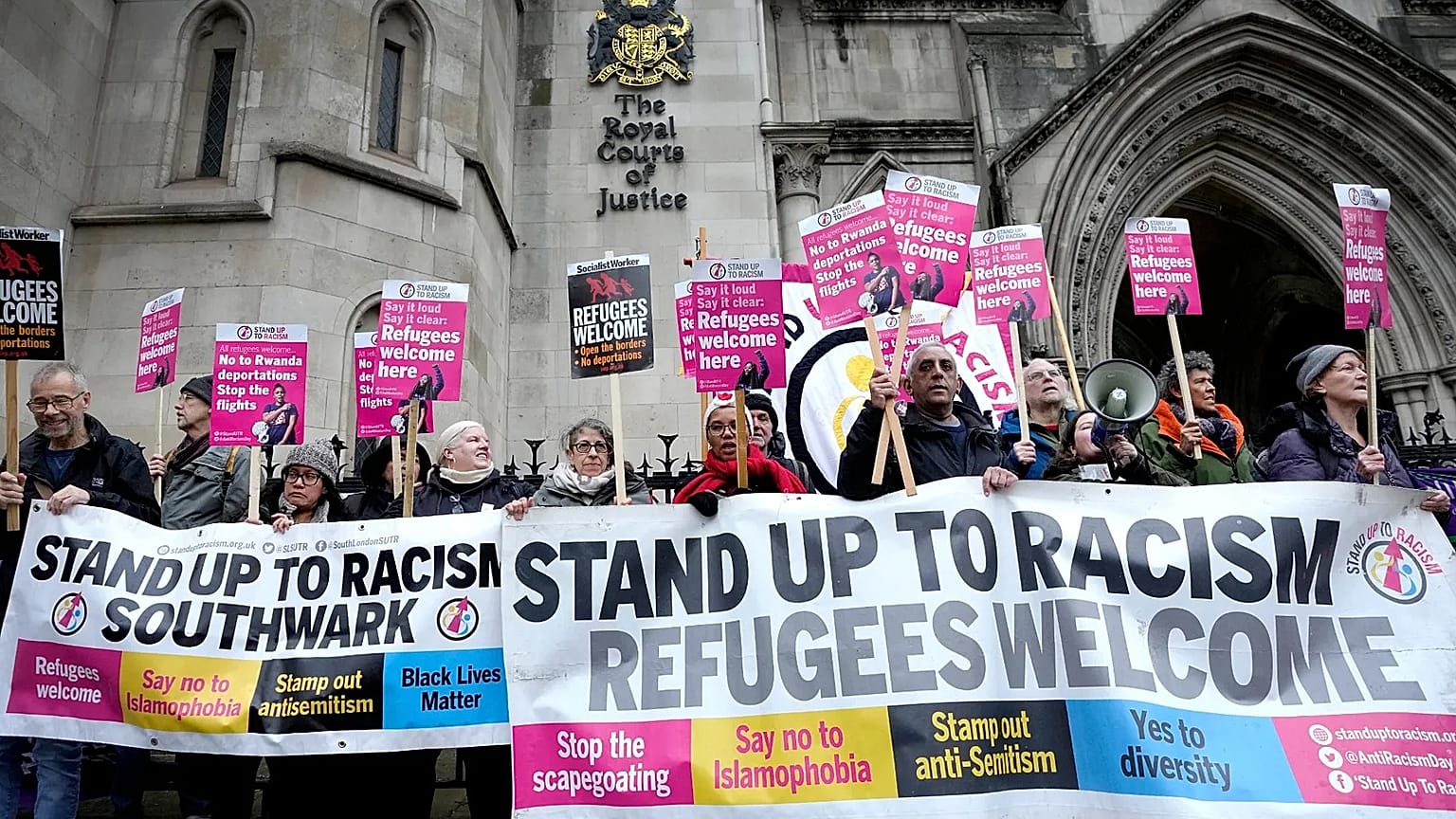 Stand Up To Racism campaigners hold banners outside the High Court in London, 19 December, 2022