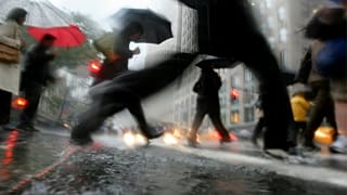 المشاة يعبرون تقاطعًا في وسط مدينة نيويورك خلال هطول أمطار غزيرة يوم الأربعاء 12 أكتوبر 2005. (تصوير: أسوشيتد برس/ بيبيتو ماثيوز)