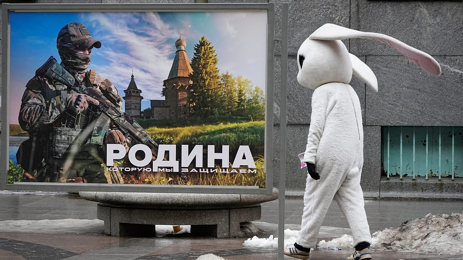 FILE: A street performer walks past a patriotic billboard showing a Russian serviceman and the slogan "The Motherland that we defend" in St. Petersburg, Russia, March 14, 2023