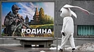 FILE: A street performer walks past a patriotic billboard showing a Russian serviceman and the slogan "The Motherland that we defend" in St. Petersburg, Russia, March 14, 2023