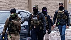 DATEI: ICE-Agenten, von denen einer eine "NOT ICE"-Gesichtsbedeckung trägt, gehen in der Nähe ihrer Fahrzeuge, Richfield, MN, 15. Januar 2026