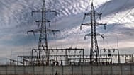 A woman walks by an electrical power distribution station in the Danube port city of Calarasi, southern Romania, Sunday, Dec. 11, 2011. 