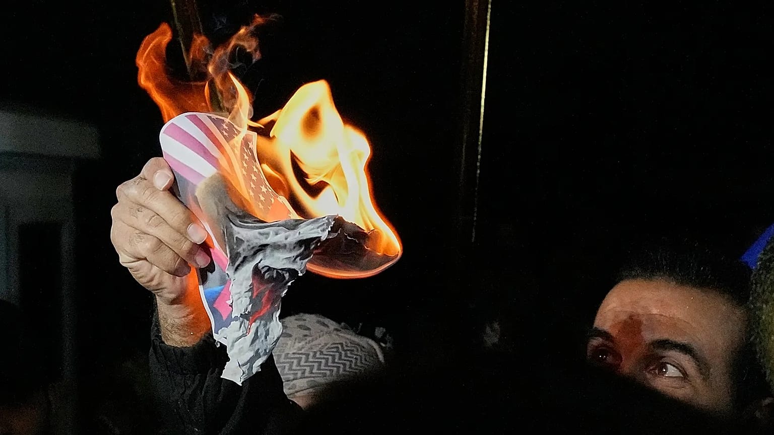 A protester holds an image of a US flag at a protest in Baghdad, 28 January, 2026