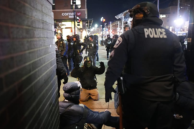 A protester raises their arms on the ground as law enforcement make arrests outside the Graduate by Hilton Minneapolis hotel on Wednesday, Jan. 28, 2026, in Minneapolis. 