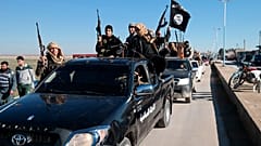 So-called Islamic State group militants drive in a convoy through Tel Abyad, northeast Syria, undated