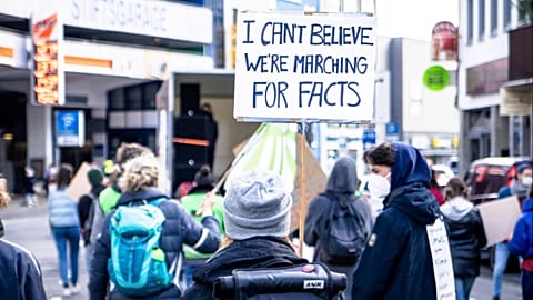 A protestor holding a sign reading "I can't believe we're marching for facts". 