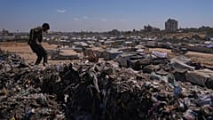 شاب فلسطيني يمشي فوق كومة من القمامة في مخيم مؤقت للنازحين في زاوية، وسط قطاع غزة، السبت 20 سبتمبر 2025