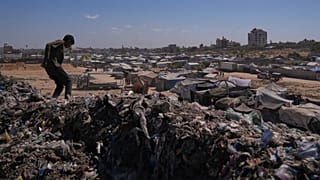 شاب فلسطيني يمشي فوق كومة من القمامة في مخيم مؤقت للنازحين في زاوية، وسط قطاع غزة، السبت 20 سبتمبر 2025