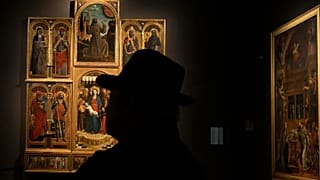 A visitor watches the painting “Madonna Enthroned with the Christ Child Angels and Saints” by Niccolo' de Liberatore in Milan, 4 December, 2024