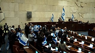لفّ مشرّعون إسرائيليون أنفسهم بالعلم الوطني احتجاجاً داخل البرلمان الإسرائيلي (الكنيست
