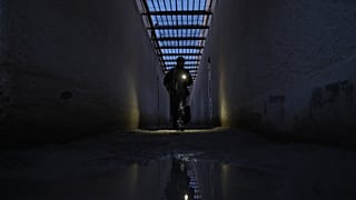 مقاتل من الحكومة السورية يسير عبر ممر داخل سجن في بلدة شدادة شمال شرق سوريا