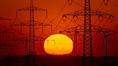 Die Sonne geht am 15. Mai 2022 am Stadtrand von Frankfurt am Main hinter Strommasten auf.