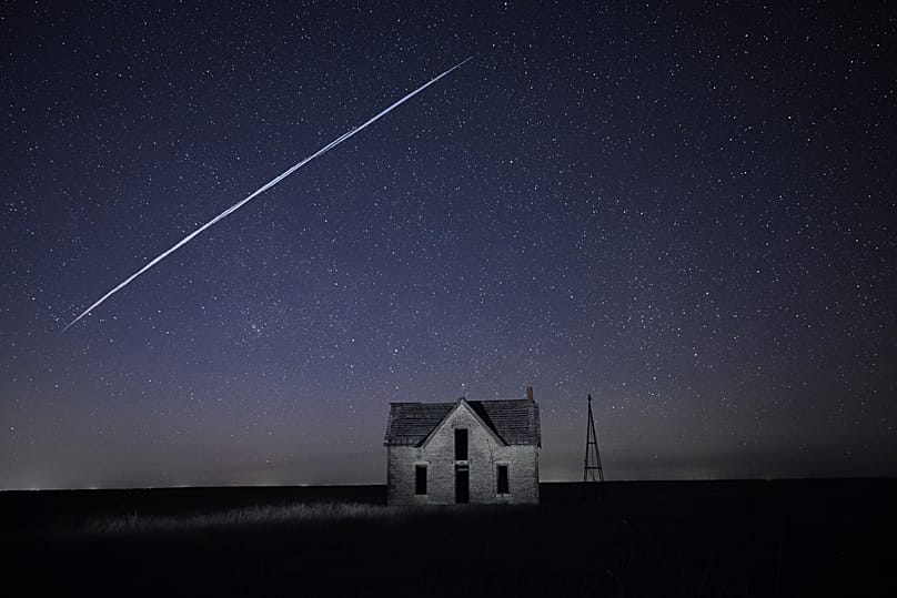 In this long exposure photo, a string of SpaceX Starlink satellites pass over a house near Florence, 6 May, 2021 