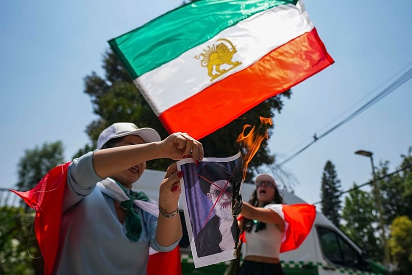 أحد المتظاهرين يحرق ملصقا للمرشد الأعلى الإيراني آية الله علي خامنئي، خلال تجمع دعما للاحتجاجات المناهضة للحكومة في إيران، تشيلي، بتاريخ 20 يناير 2026.