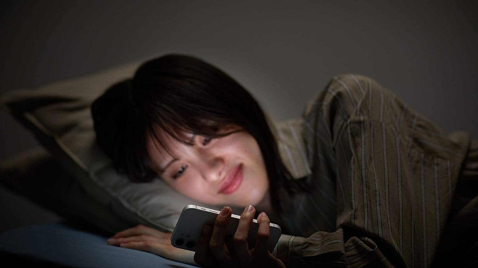 Fille allongée dans son lit, faisant défiler son téléphone tard dans la nuit
