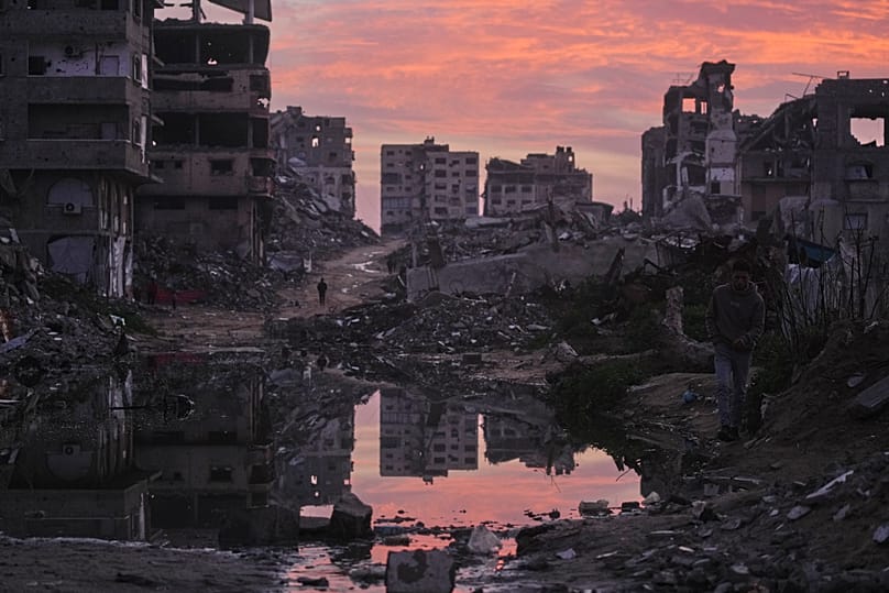 Palestinians walk amid buildings destroyed by Israeli air and ground operations in Gaza City, 29 January, 2026