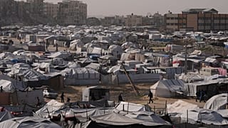 الفلسطينيون يسيرون بين الخيام في مخيم مؤقت للنازحين في خانيونس، جنوب قطاع غزة، يوم الثلاثاء، 27 يناير 2026. (تصوير: عبد الكريم حنا/أسوشيتد برس)