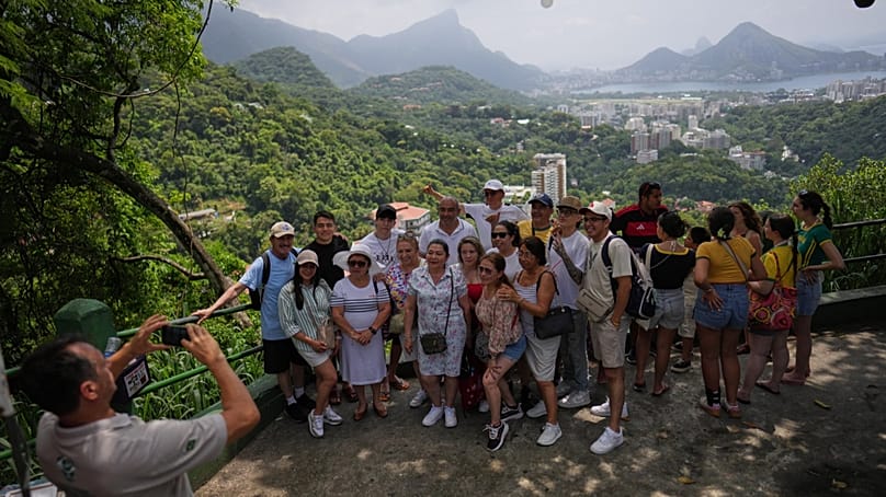 Ein Guide fotografiert Touristinnen und Touristen an einem Aussichtspunkt in der Favela Rocinha, als Rio de Janeiro 2025 eine Rekordzahl internationaler Gäste verzeichnete, Dienstag, 27. Januar.