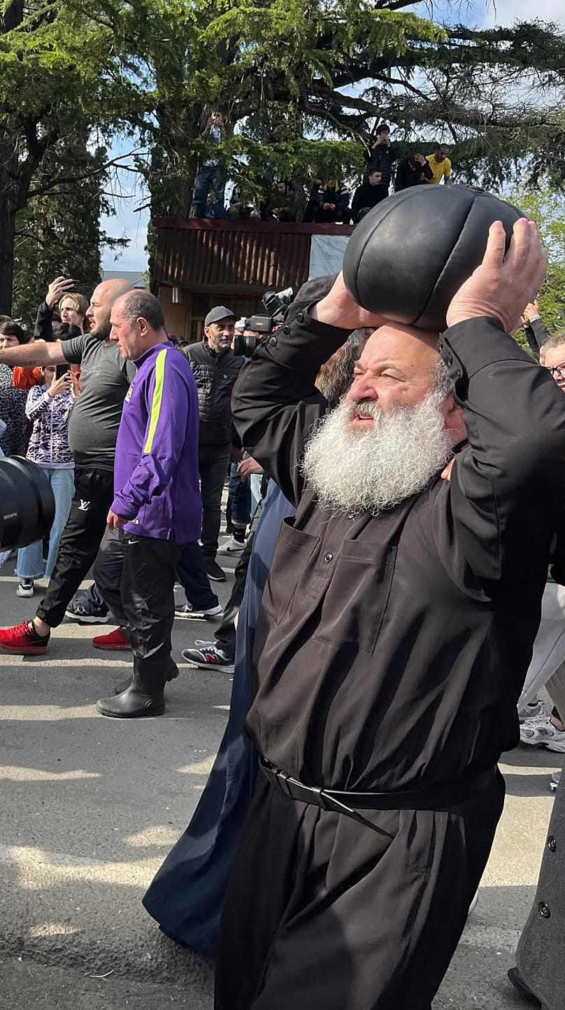 Un prete porta una pesante palla usata per il lelo burti nella Georgia occidentale
