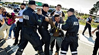 Police grab a refugee as hundreds of refugees walk in Southern Jutland motorway near Padborg, 9 September, 2015