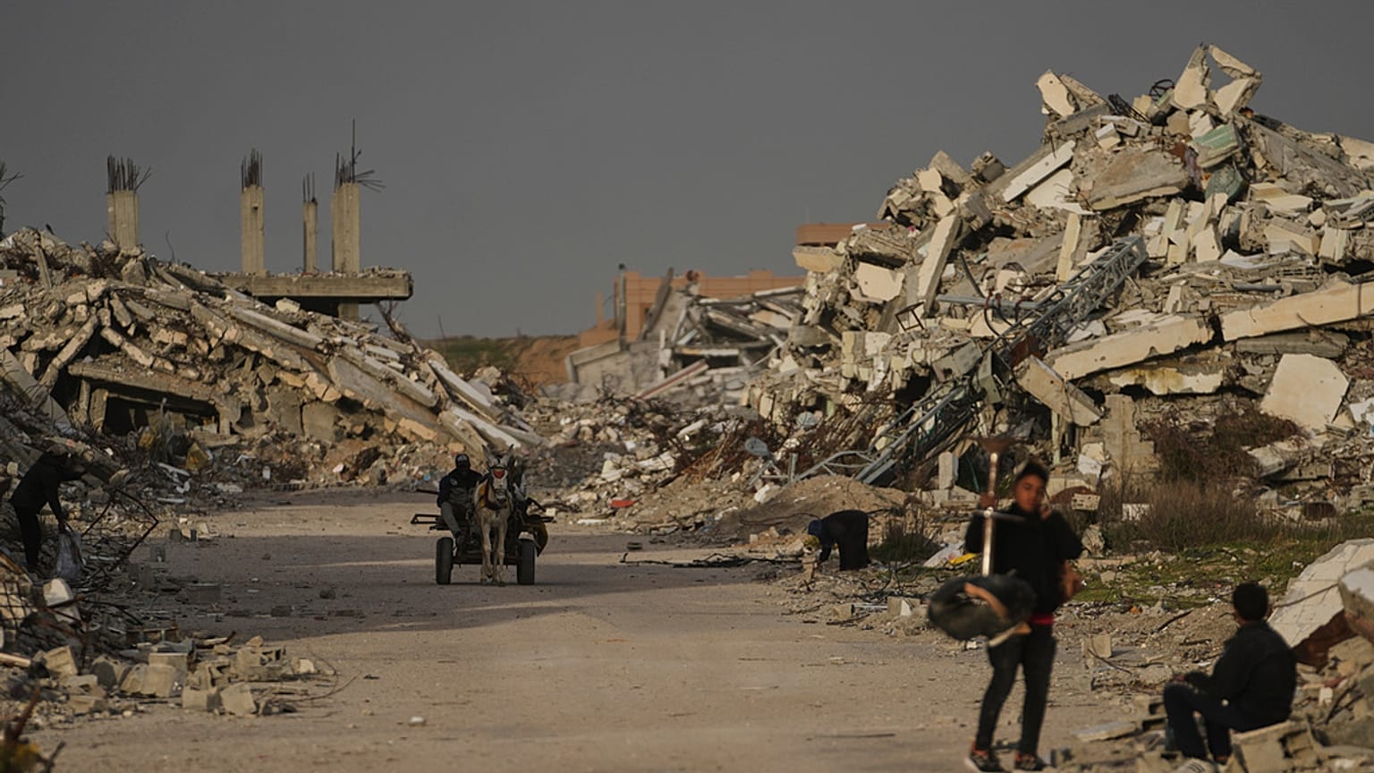 فلسطينيون يسيرون وسط الأنقاض التي خلفها الهجوم الجوي والبري الإسرائيلي في الزهراء وسط قطاع غزة، الأربعاء 28 يناير 2026. 