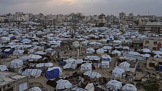 يسير أشخاص بين خيام تؤوي نازحين فلسطينيين وسط الدمار الذي خلّفته الهجمات الجوية والبرية الإسرائيلية في مدينة غزة، الأربعاء 28 يناير/كانون الثاني 2026. (أسوشيتد برس/جهد الشرفي)