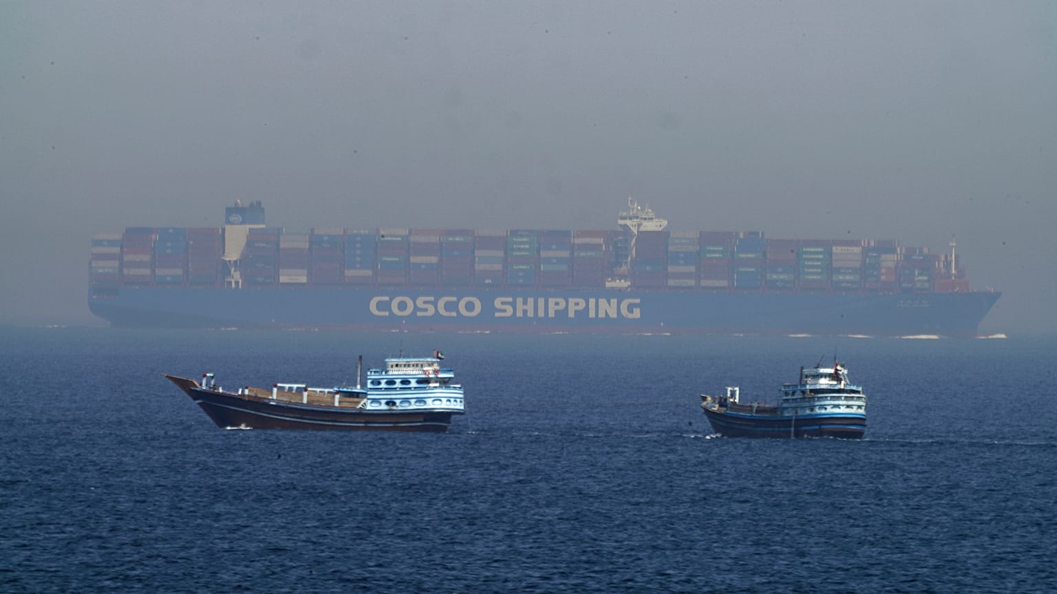 ARCHIVE: Two traditional dhows sail by a large container ship in the Strait of Hormuz, May 19, 2023. 