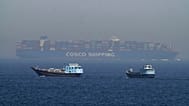 ARCHIVE: Two traditional dhows sail by a large container ship in the Strait of Hormuz, May 19, 2023. 