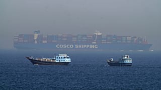 ARCHIVE: Two traditional dhows sail by a large container ship in the Strait of Hormuz, May 19, 2023. 