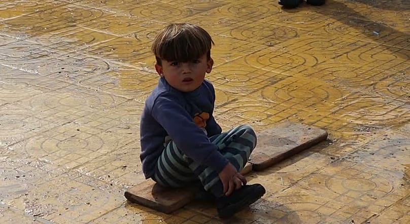 طفل نازح يجلس في باحة مدرسة تحوّلت إلى مكان لإيواء النازحين الأكراد.