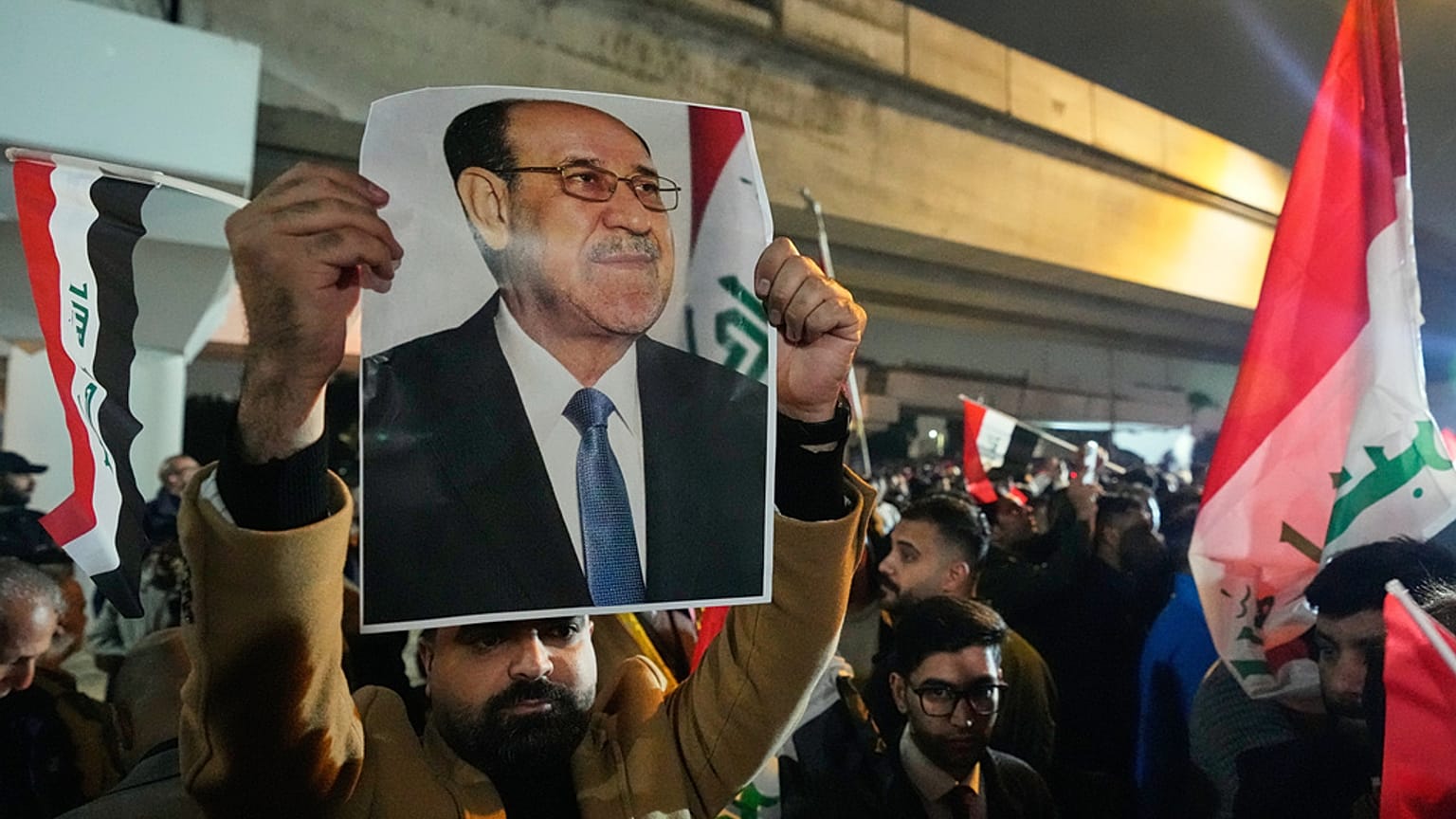 رجل عراقي يحمل صورة رئيس الوزراء السابق نوري المالكي، خلال احتجاج على جسر يؤدي إلى المنطقة الخضراء المحصنة حيث تقع السفارة الأمريكية في بغداد، العراق، الخميس 29 يناير 2026. 