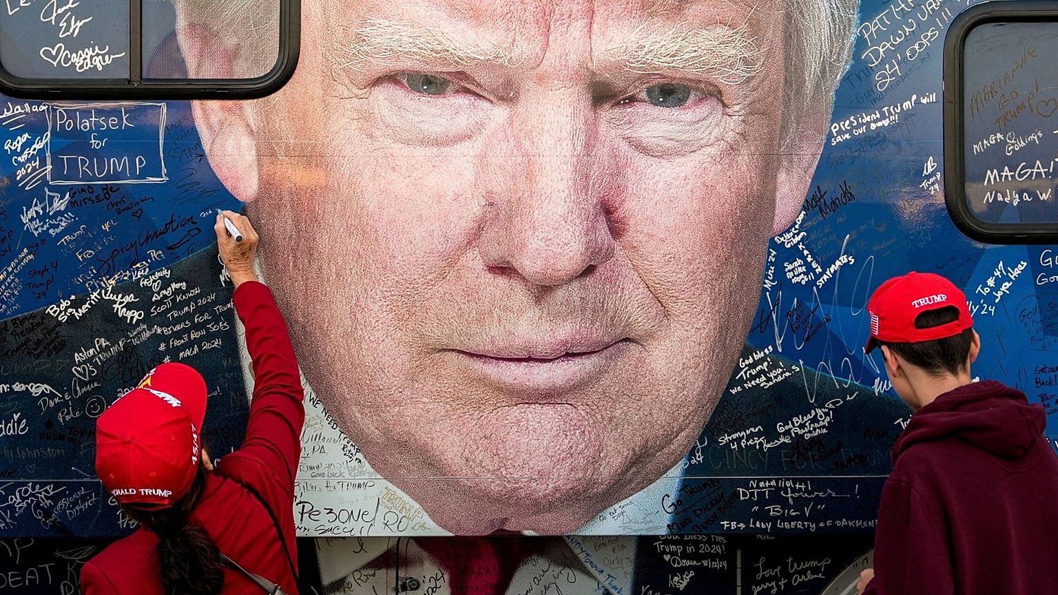 حامیان دونالد ترامپ پیش از گردهمایی انتخاباتی در پنسیلوانیا، در تاریخ ۵ اکتبر ۲۰۲۴، در حال امضای یک اتوبوس ستاد انتخاباتی