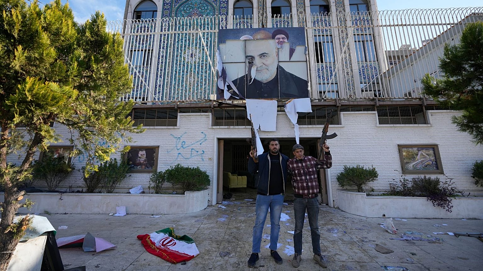 Syrian opposition fighters stand at the damaged entrance of the Iranian embassy in Damascus, Syria
