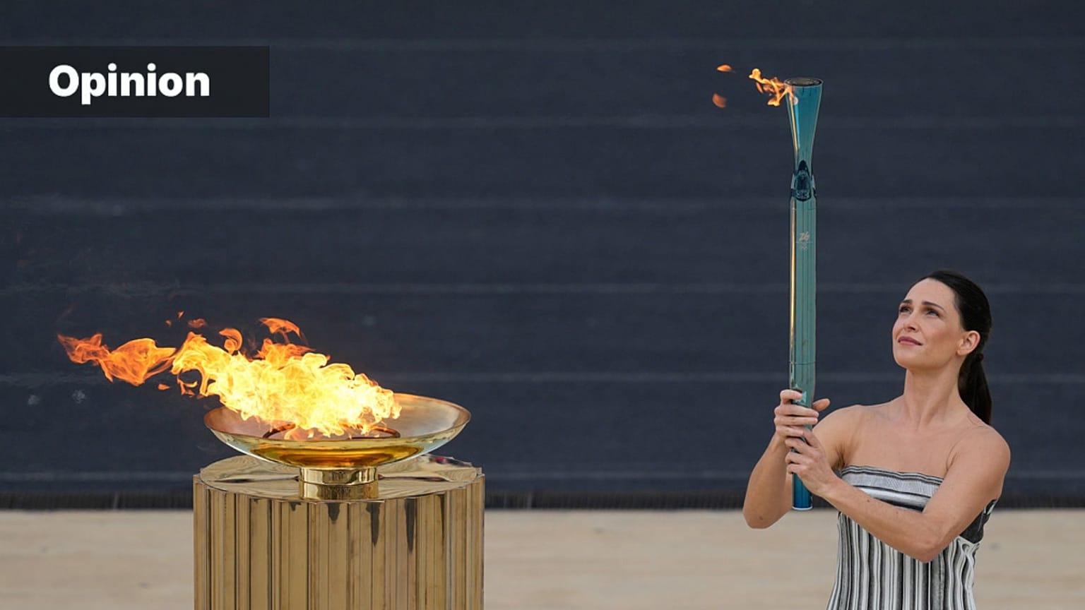 FILE: Greek actress Mary Mina, playing the role of High Priestess, lights a torch from the cauldron during the Olympic flame handover ceremony in Athens, 4 December 2025. 