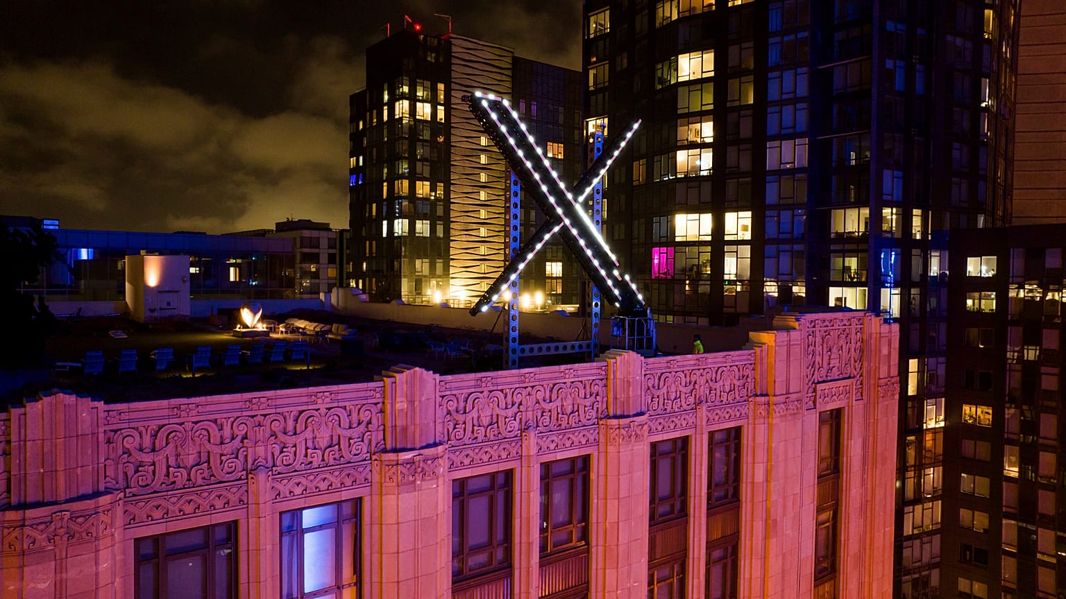 Workers install lighting on an "X" sign atop the company headquarters, formerly known as Twitter, in downtown San Francisco, July 28, 2023.