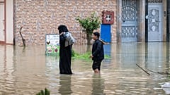 أم وابنها يفران عبر شارع غارق بالمياه بعد هطول أمطار غزيرة في مدينة قصر الكبير بالمغرب، يوم الجمعة 30 يناير 2026. (تصوير: أسوشيتد برس)