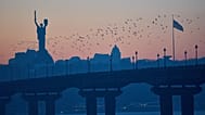 Birds fly over the city at sunset, with the Motherland Monument in the background, in Kyiv, Ukraine, Wednesday, Jan. 21, 2026
