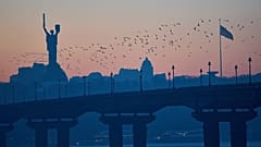  Vögel fliegen bei Sonnenuntergang über die Stadt, mit dem Mutterland-Denkmal im Hintergrund, in Kiew, Ukraine, Mittwoch, 21. Januar 2026