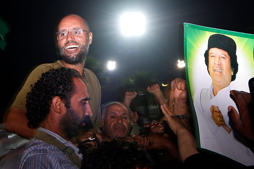 File - Moammar Gadhafi's son, Seif al-Islam, top left, gestures to troops loyal to his father in Tripoli, Libya, Tuesday, Aug. 23, 2011