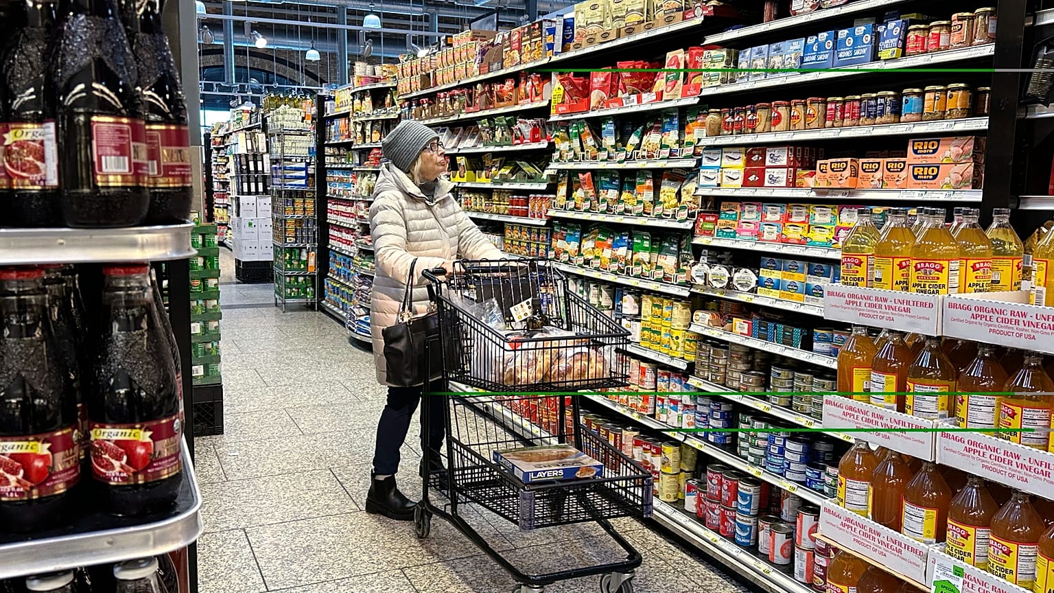 Una donna controlla i prezzi mentre fa la spesa in un supermercato.