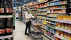 In einem Supermarkt vergleicht eine Frau beim Einkaufen die Preise.