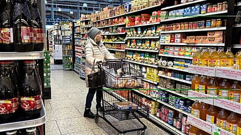 A woman checks prices as she shops at a grocery store.