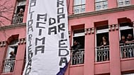 A banner with the words "solidarity above property" is unfurled from a residential building, during a demonstration to demand solutions for Portugal's housing crisis, 2023. 