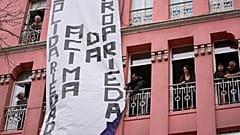 Uma faixa com as palavras "solidariedade acima da propriedade" é desfraldada de um edifício residencial, durante uma manifestação para exigir soluções para a crise da habitação em Portugal, 2023. 