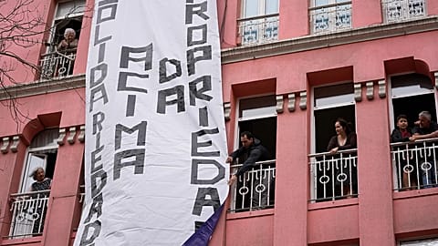Uma faixa com as palavras "solidariedade acima da propriedade" é desfraldada de um edifício residencial, durante uma manifestação para exigir soluções para a crise da habitação em Portugal, 2023. 
