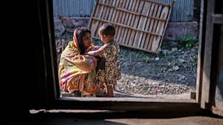 Tekstil işçisi Dipu Chandra Das'ın eşi Meghna Rani, kızıyla Bangladeş'in Tarakanda köyündeki evlerinin dışında.