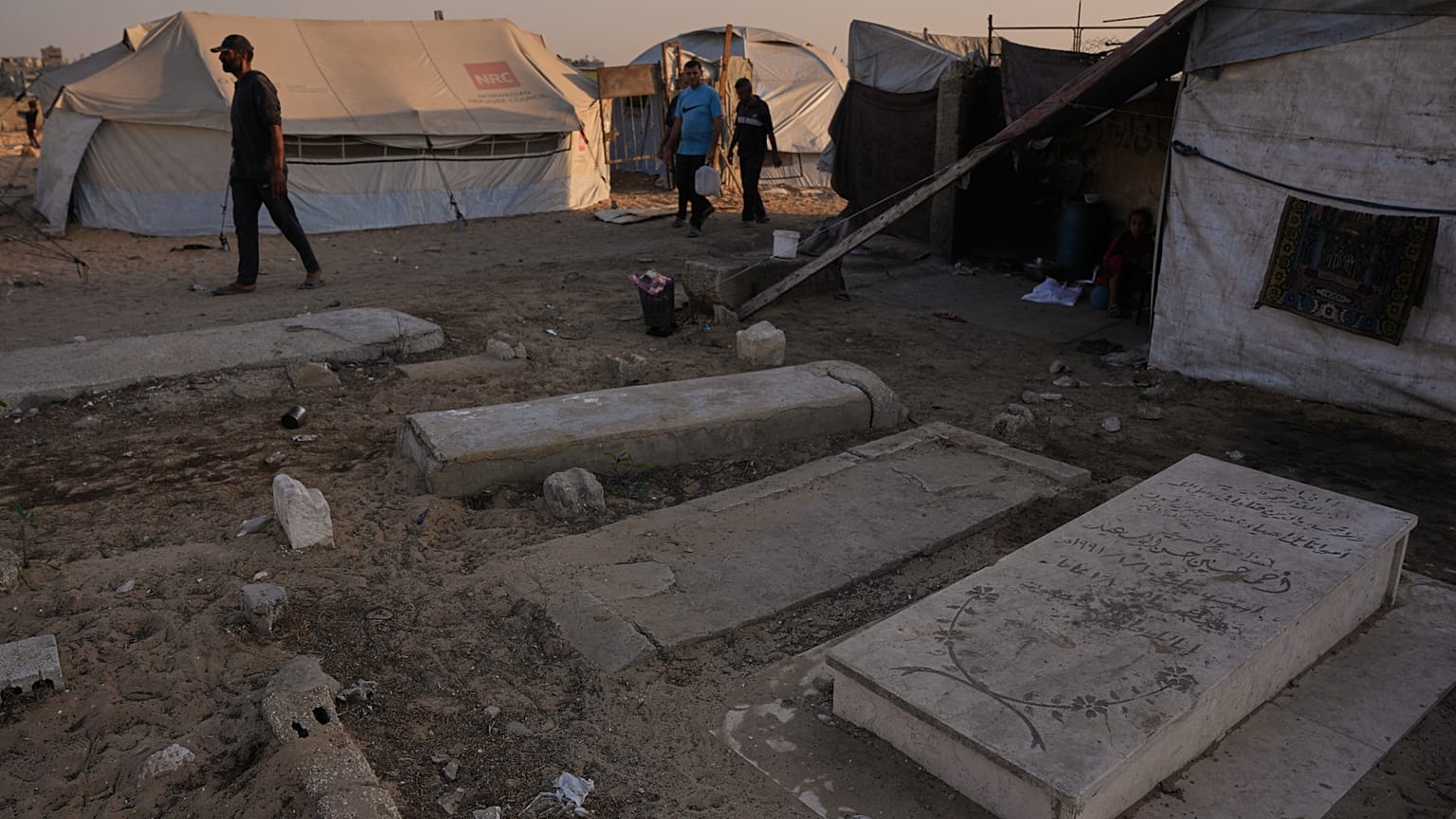 فلسطينيون يمرون بجوار خيام مؤقتة نُصبت في مقبرة خان يونس، جنوب قطاع غزة، يوم الجمعة 31 أكتوبر/تشرين الأول 2025. (صورة من وكالة أسوشييتد برس/عبد الكريم حنا)