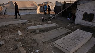 Palestinesi camminano davanti a tende temporanee erette nel cimitero di Khan Younis, nel sud della Striscia di Gaza, venerdì 31 ottobre 2025. (Foto AP/Abdulkarim Hanna)